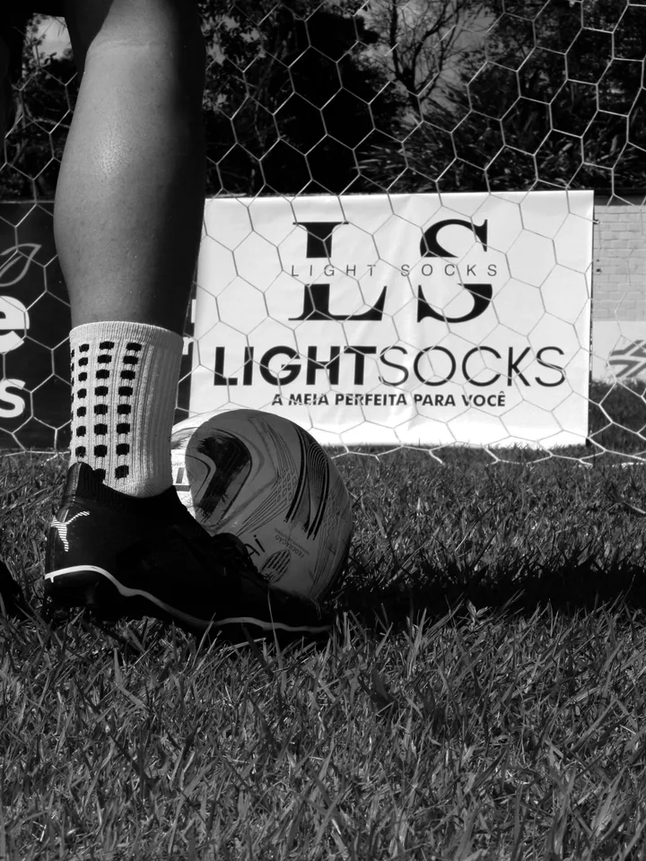Jogadores com Light Socks em frente à placa da marca no gol